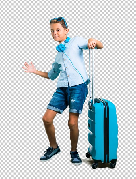 Kid con occhiali da sole e cuffie che viaggiano con la sua valigia orgogliosa