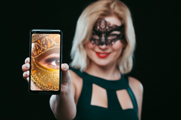 PSD kobieta z karnawał maską pokazuje smartphone mockup