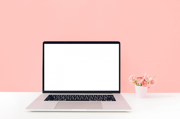 PSD laptop with white blank screen and flowers in vase on table