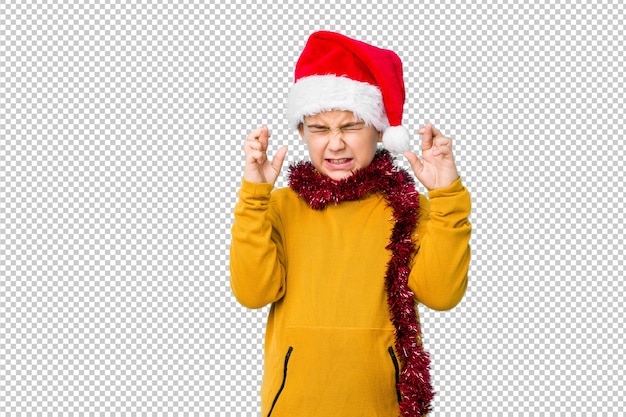 Little boy celebrating christmas day wearing a santa hat isolated crossing fingers for having luck