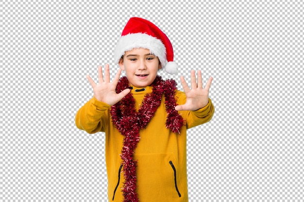 Мальчик празднуя рождество нося шляпу santa изолировал показывать 10 с руками.