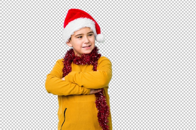 Little boy celebrating christmas day wearing a santa hat isolated smiling confident with crossed arms.