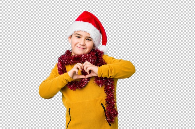 PSD il ragazzino che celebra il giorno di natale che porta un cappello di santa ha isolato sorridere e mostrare una forma del cuore con le mani.