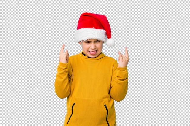 Ragazzino che celebra il giorno di natale che porta un cappello di santa che mostra gesto della roccia con le dita