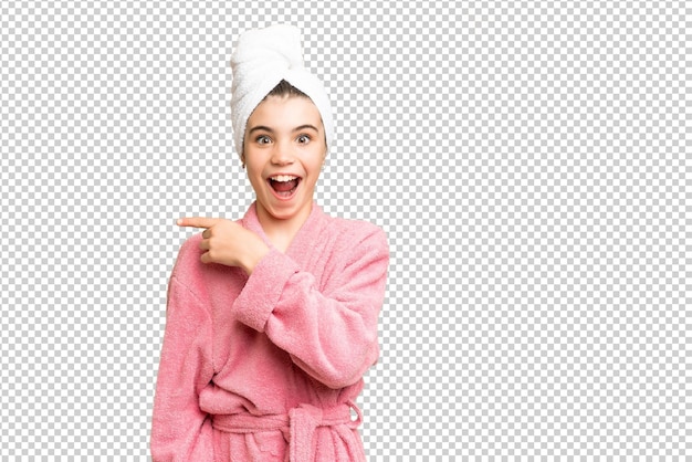 little girl in a bathrobe over isolated chroma key background surprised and pointing side