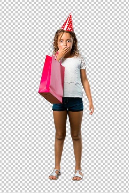 Little girl at a birthday party holding a gift bag covering mouth with hands