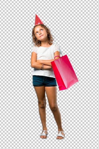 Little girl at a birthday party holding a gift bag stand and looking up