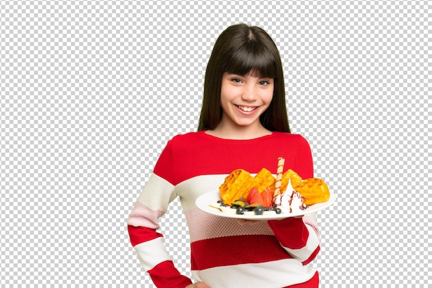 little girl holding waffles over isolated chroma key background posing with arms at hip and smiling