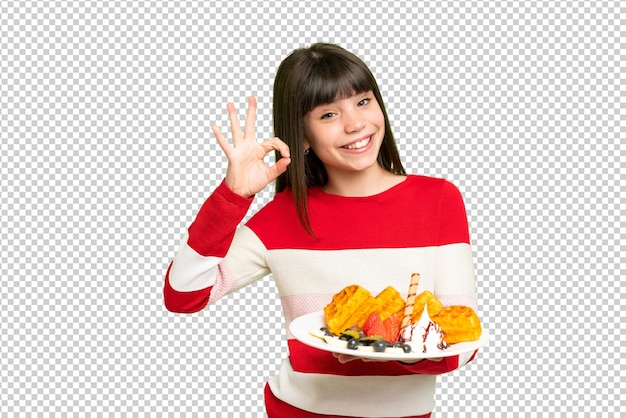 little girl holding waffles over isolated chroma key background showing ok sign with fingers