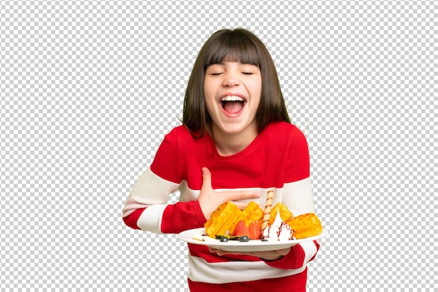 Little girl holding waffles over isolated chroma key background smiling a lot
