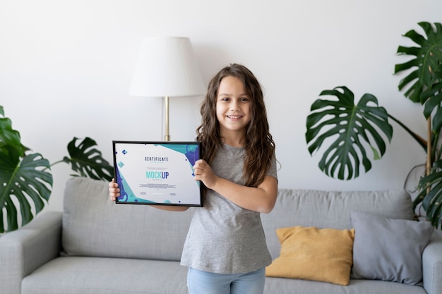 PSD little girl at home holding a certificate mock-up