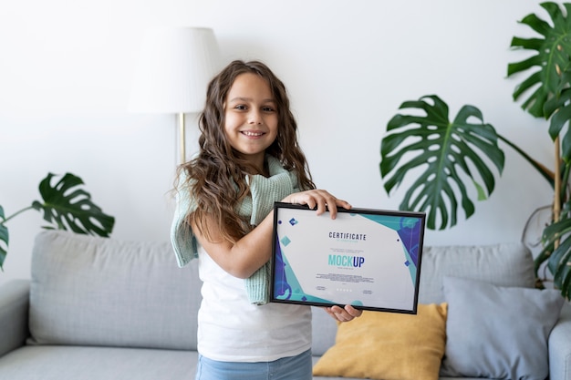 Little girl at home holding a certificate mock-up