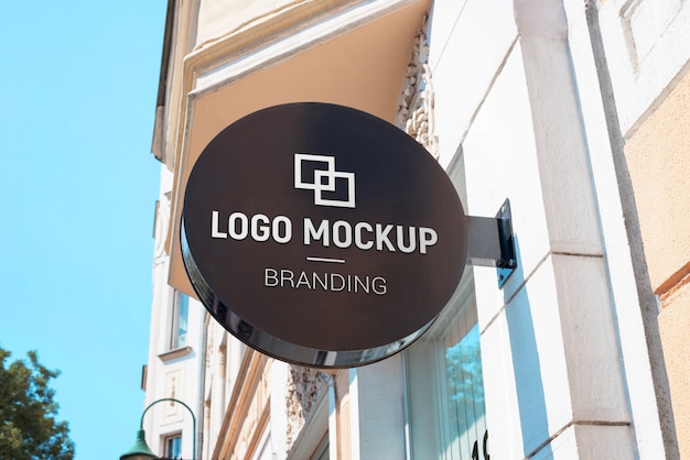 Logo mockup op ronde straatnaambord boven de winkel. Moderne, zwarte bewegwijzering