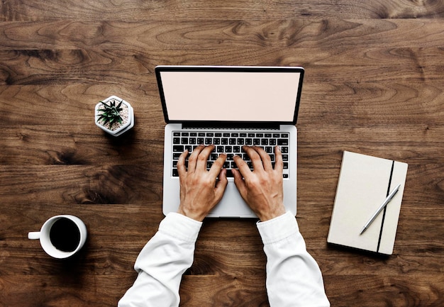 Luchtbeeld van een man die een laptop op een houten tafel gebruikt