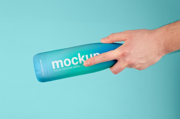 Mano maschio che tiene mock-up di bottiglia thermos blu