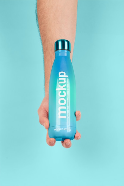 Mano maschio che tiene mock-up di bottiglia thermos blu