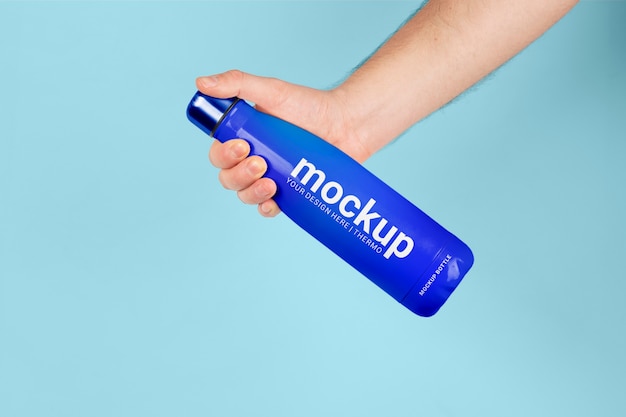 PSD male hand holding mock-up of blue thermos bottle