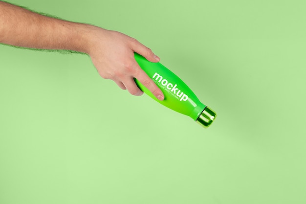 PSD male hand holding mock-up of green thermos bottle