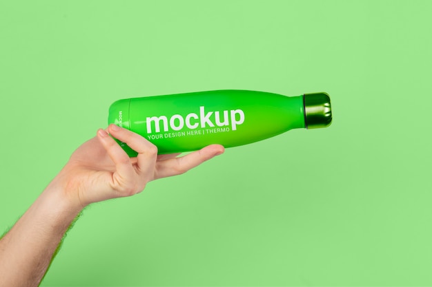 PSD male hand holding mock-up of green thermos bottle