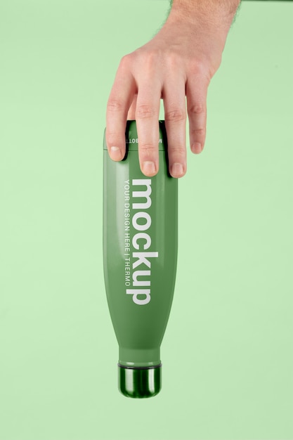 Mano maschio che tiene il modello della bottiglia di thermos verde