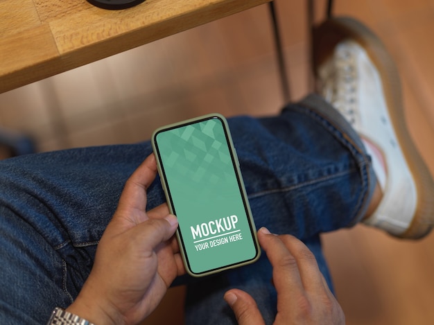 Male hand using mockup smartphone while sitting in office room