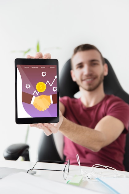 Male student at desktop holding tablet