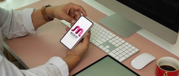 Uomo che utilizza smartphone mockup sulla scrivania in ufficio