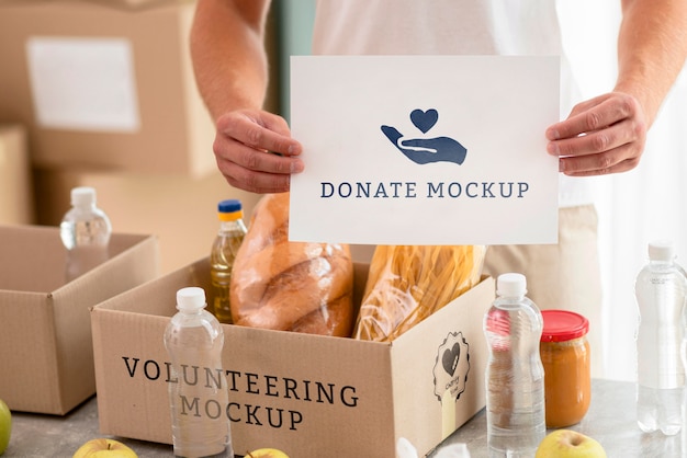 Male volunteer holding blank paper with box of food for donation