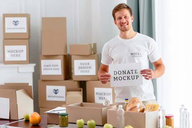 Male volunteer holding blank paper with food boxes for donation