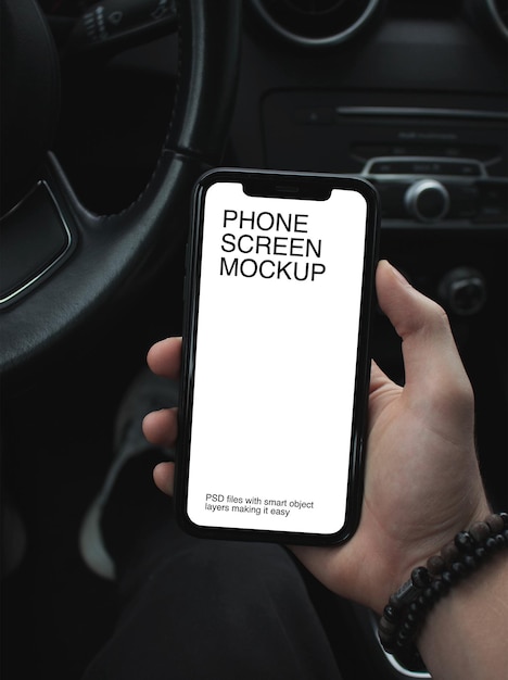 A man in the car and holding a cell phone