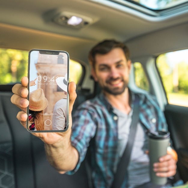 Man in car showing smartphone mockup