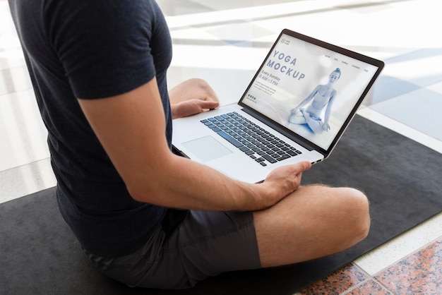 Man doet yoga met laptop mockup-ontwerp