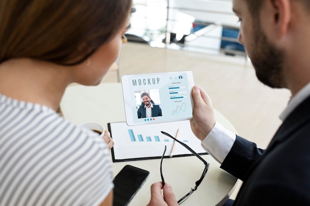 Man en vrouw die een tablet op het werk bekijken