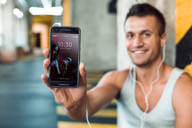 PSD man in gym holding smartphone mockup