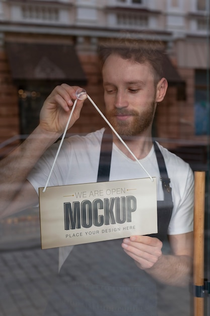 Man hanging we are open sign mock-up in business window