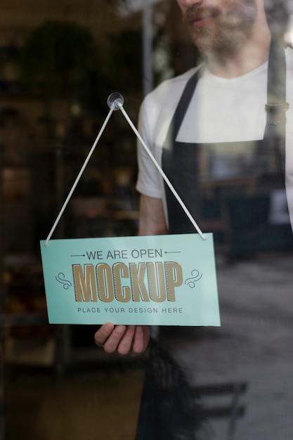 Man hanging we are open sign mock-up in business window