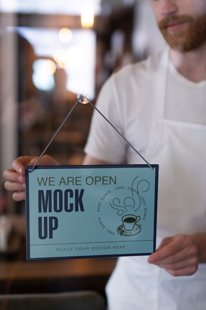 PSD man hanging we are open sign mock-up in business window