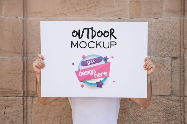man presenting poster mockup in front of brick wall