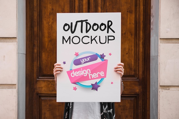 PSD man presenting poster mockup in front of door