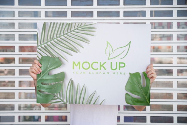 Uomo che presenta poster mockup davanti al cancello