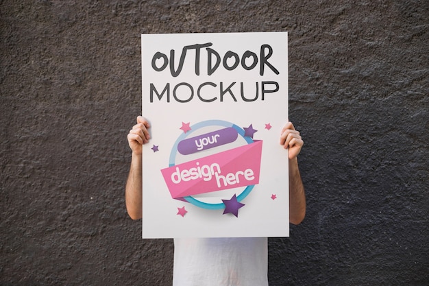 Uomo che presenta poster mockup davanti al muro