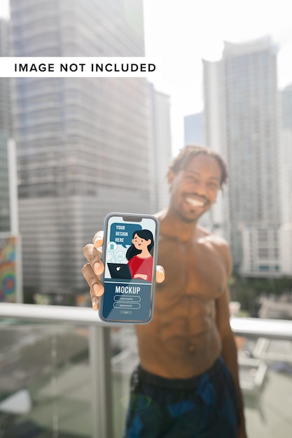 PSD man showing smartphone outdoors with buildings background mockup