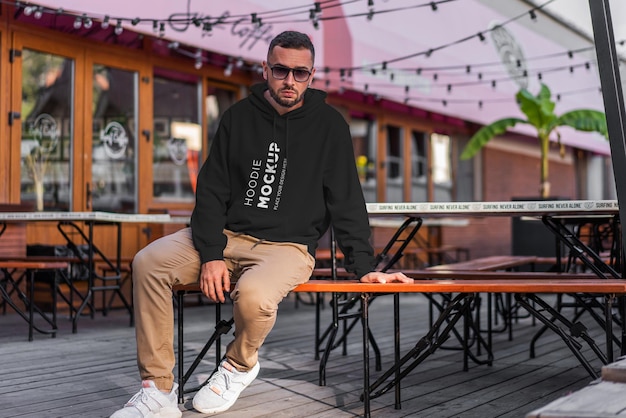 PSD man sitting on a bench wearing a black hoodie mockup