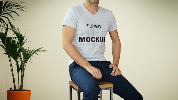 A man sitting on a stool wearing a t shirt mockup