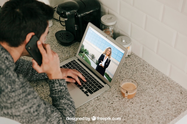 Man using laptop and making phone call