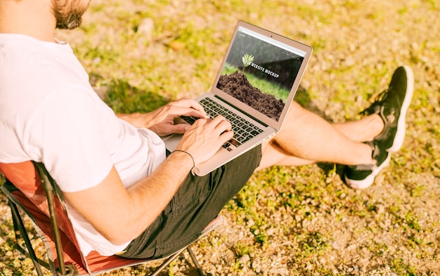 PSD man using laptop mockup in nature