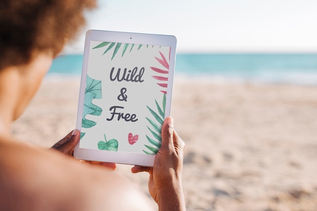 Uomo che utilizza tablet mockup in spiaggia