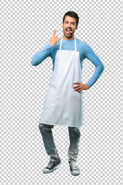 Man wearing an apron showing tongue at the camera having funny look and taking out the horns