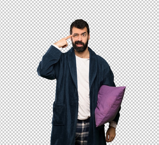 man with beard in pajamas making the gesture of madness putting finger on the head