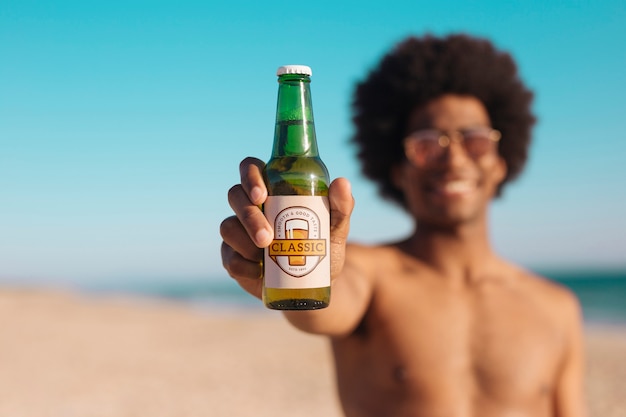 Uomo con il modello di bottiglia di birra in spiaggia